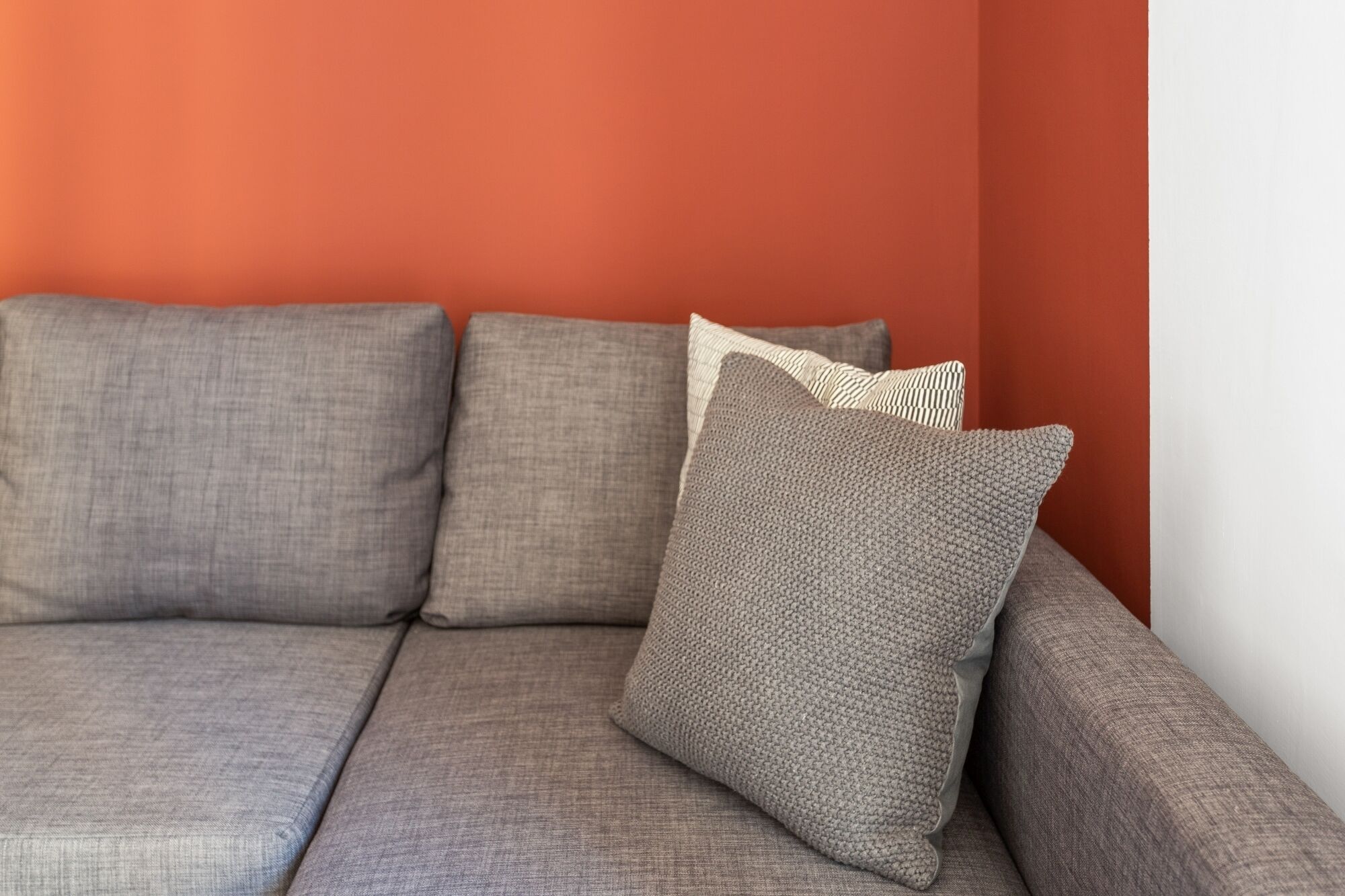 Un canapé modulable avec plusieurs coussins, placé contre un mur rouge.