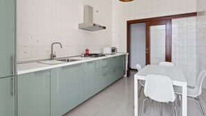 Una cocina moderna con estufa a gas, pileta y un comedor con mesa y sillas.