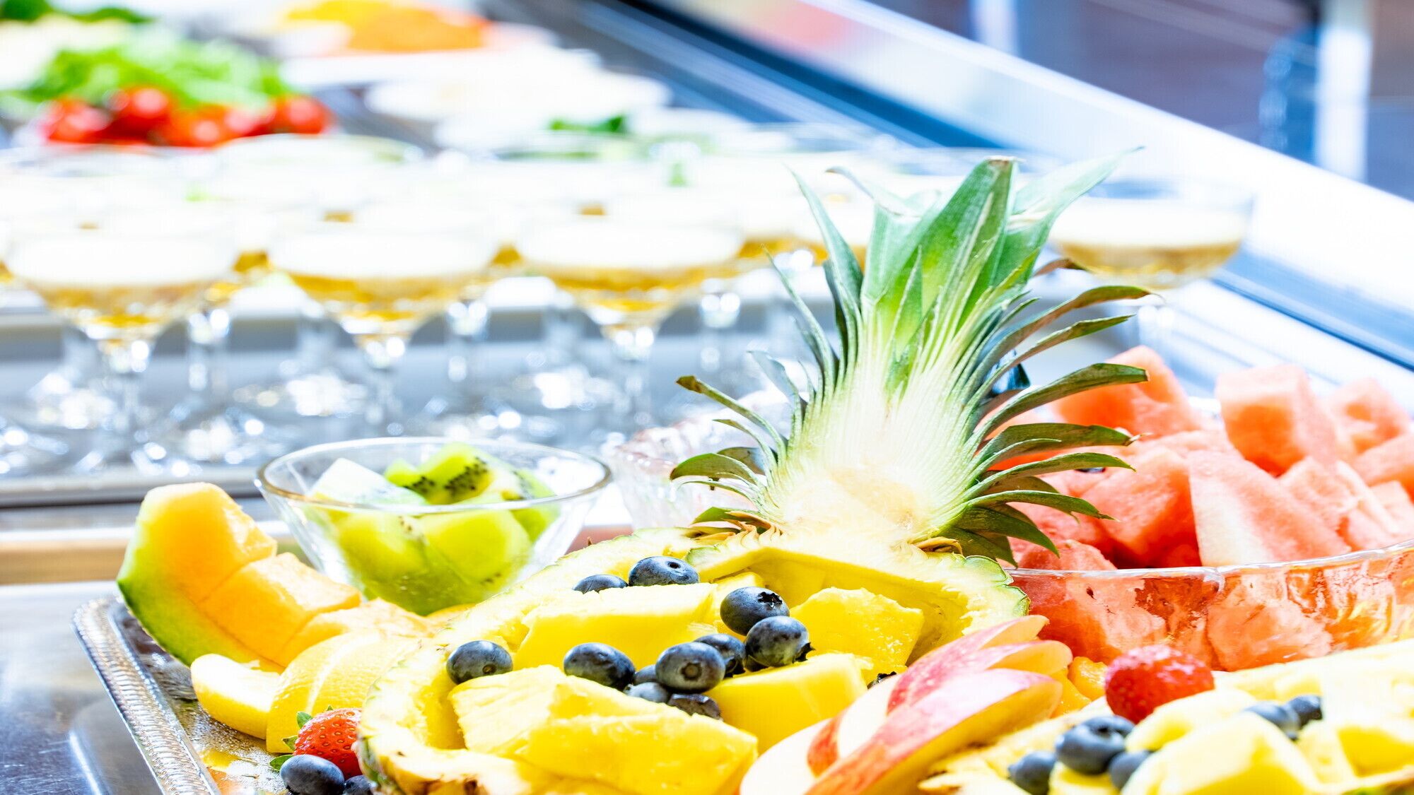 Un buffet proposant une variété de fruits et un verre de vin.