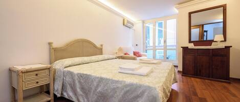 A bedroom with a bed, bedside table, dresser, and a large mirror.
