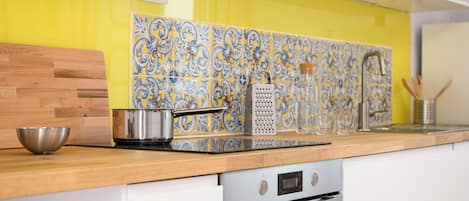 Une cuisine avec un revêtement mural jaune, un plan de travail en bois, des appareils en acier inoxydable et des meubles blancs.