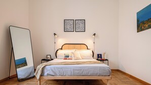A neatly arranged bedroom with a wooden bed, a bedside table with a lamp, and a large mirror leaning against the wall. - Viale Calascione 7 (Naples)