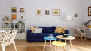 A modern living room with a blue sofa, white shelves, and a wooden floor. - Viale Calascione 7 (Naples)