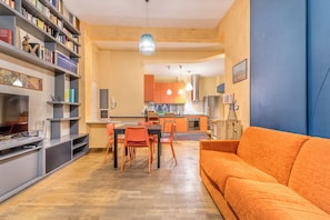 A modern living room with a sofa, a dining area with chairs, and a kitchen in the background. - Il Gazebo a Monteverde (Rome)