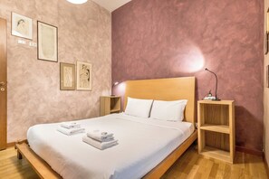 A neatly made bed with white linens and towels, a wooden headboard, and a bedside table with a lamp. - Il Gazebo a Monteverde (Rome)