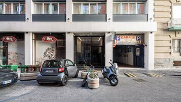 A building with a garage sign, a parked car, and a scooter.