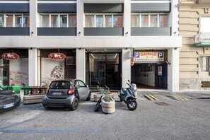 Ein Gebäude mit einer Garage, einem geparkten Auto und einem Roller.
