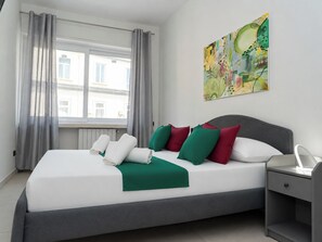 A hotel room with a bed, a bedside table, a window with curtains, and a painting on the wall. - Via Niccolò Tommaseo 4 - Appartamento 3 (Naples)