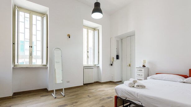 A bedroom with a bed, a wardrobe, a mirror, and a radiator. - Via Morghen 63 - Primo Piano (Naples)