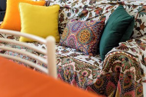A bed with a floral-patterned bedspread, a yellow pillow, and a green pillow. - Via Morghen 63 - Primo Piano (Naples)