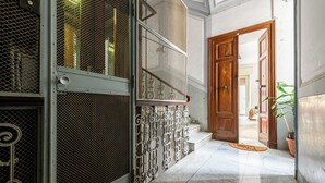 A hallway with a metal gate, a wooden door, and a potted plant. - Via Morghen 63 - Primo Piano (Naples)