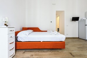 A single bed with an orange headboard, white bedding, and a wooden floor. - Via Morghen 63 - Primo Piano (Naples)