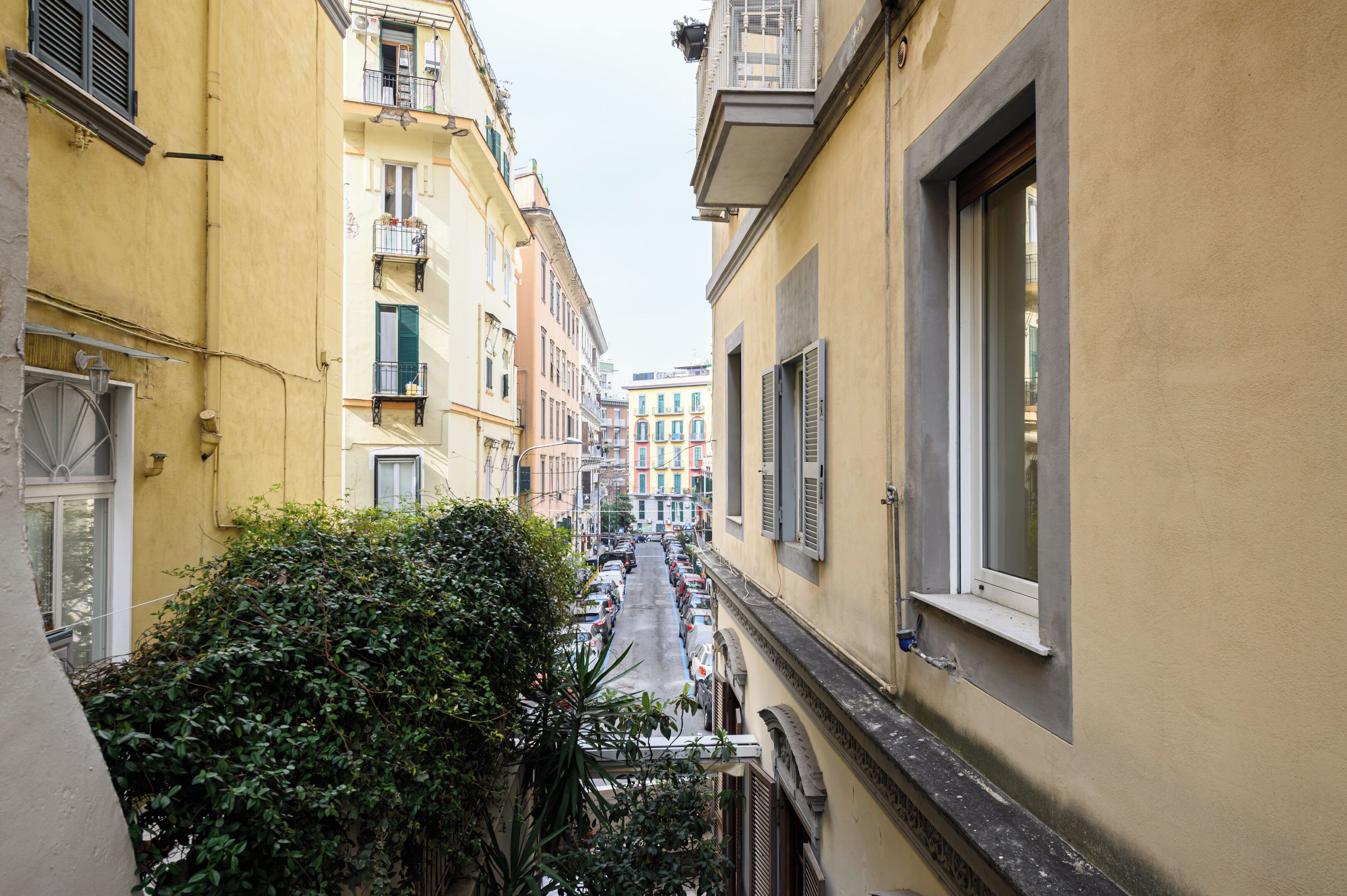 A narrow street with buildings on both sides, featuring balconies and windows.