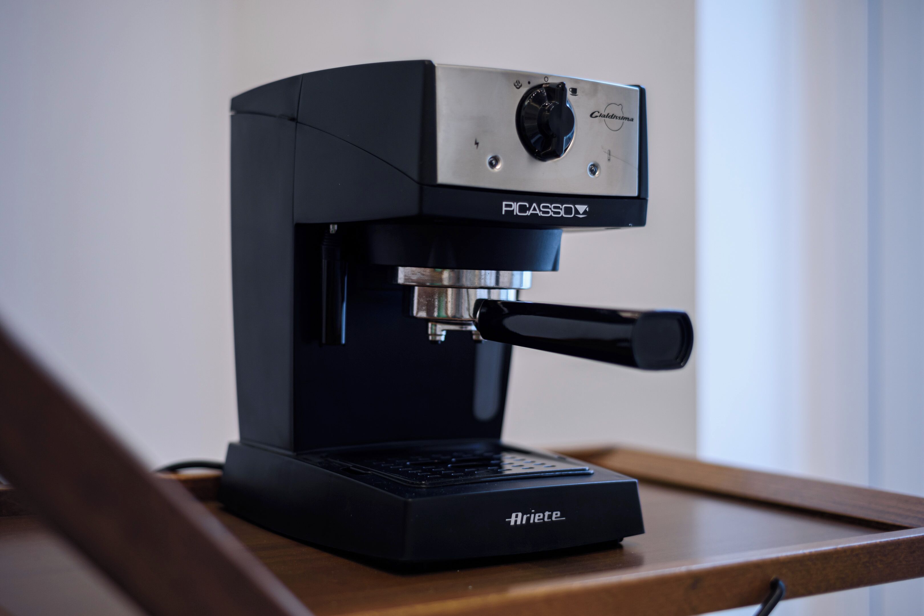Une machine à café compacte et moderne, dotée d’une interface numérique, posée sur une surface en bois.
