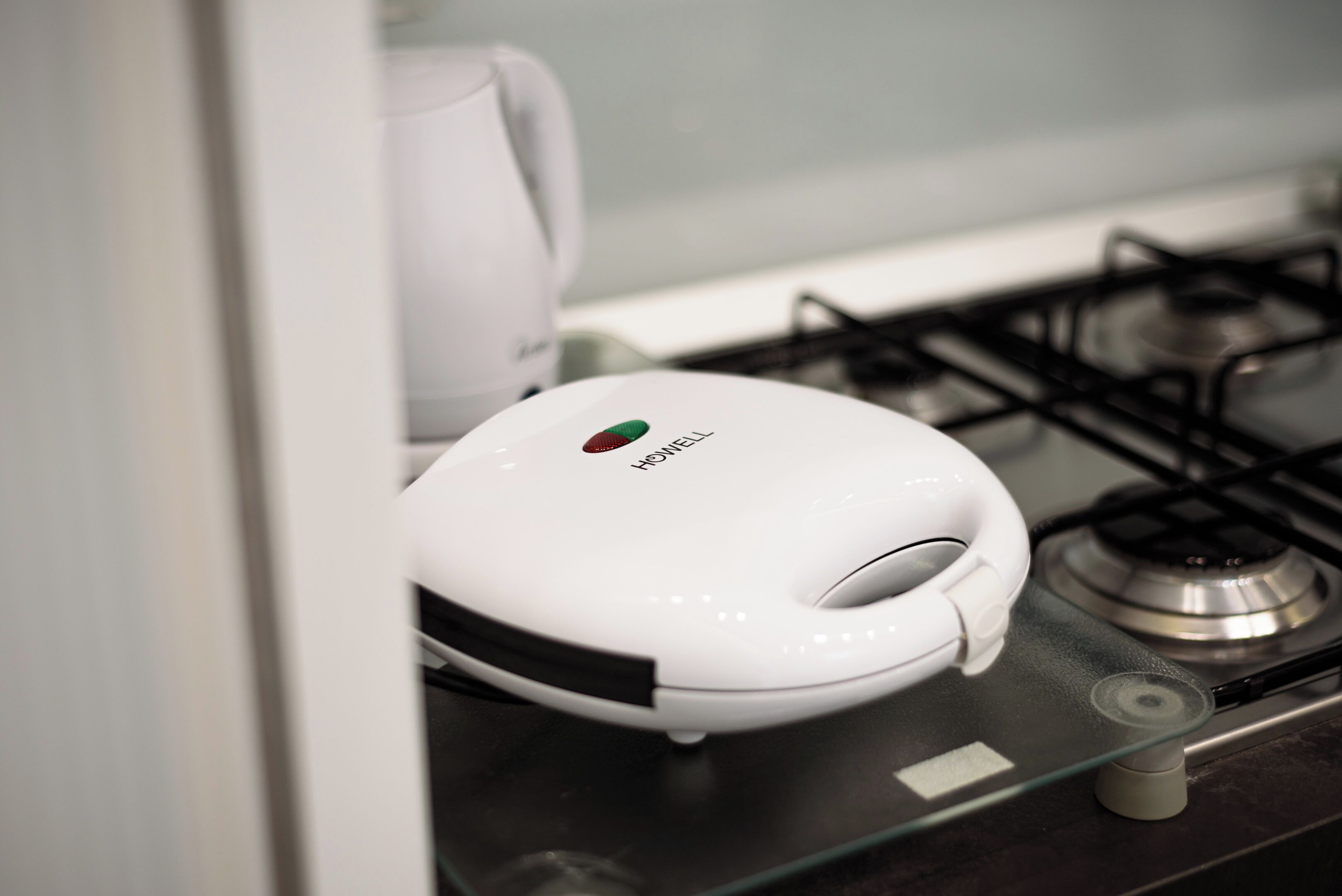 A white, modern kitchen with a gas stove and a white appliance on the counter.