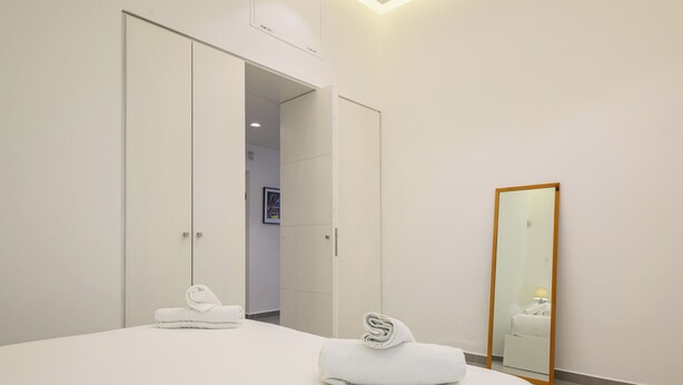 Een hotelkamer met een bed, een spiegel en een kast.
