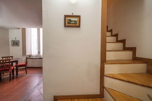 A dining area with a wooden table and chairs, a staircase with wooden steps, and a framed picture on the wall. - Il Nido (Naples)