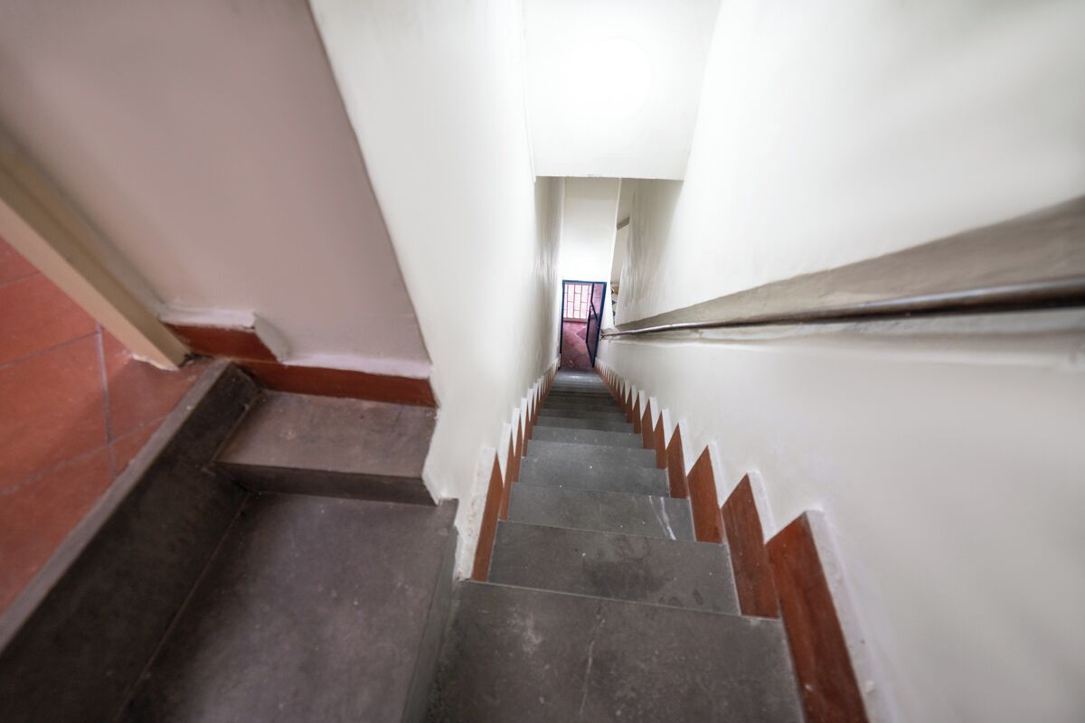 Un escalier étroit, muni d’une main courante, menant à une porte située en haut.