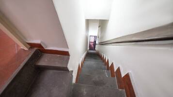 Un escalier étroit, muni d’une main courante, menant à une porte située en haut.