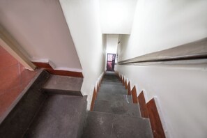 A narrow staircase with a handrail, leading to a door at the top. - Il Nido (Naples)