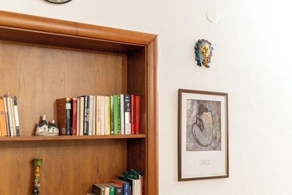 A bookshelf with books and a framed artwork on a wall. - Il Nido (Naples)