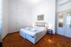 A bedroom with a bed, a nightstand, a wardrobe, and a door with frosted glass panels. - Casa Emme (Rome)