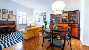 Een eetgedeelte met een houten tafel, stoelen, een piano, een bank en een kamerbreed tapijt.