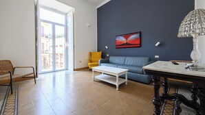 Ein Wohnzimmer mit einem blauen Sofa, einem gelben Sessel, einem weißen Couchtisch und einer dekorativen Lampe.