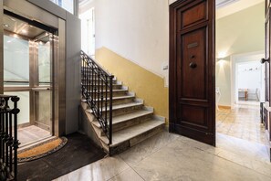 A staircase with a wooden door and a metal railing. - Via Cairoli 60 (Naples)
