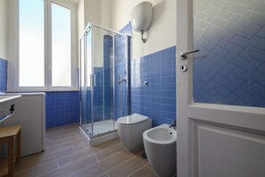 A bathroom with a glass shower enclosure, a bidet, and a toilet. - Via Cairoli 60 (Naples)