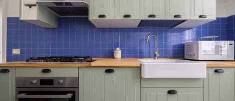 A kitchen with green cabinets, a microwave, a sink, and a stove.