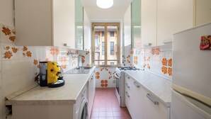 Una cucina piccola con mobili bianchi, una lavatrice e una macchina da caffè gialla.