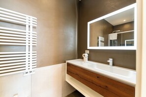Une salle de bain moderne avec un meuble-lavabo blanc, un grand miroir et un porte-serviettes.