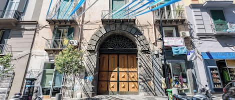 Um edifício com uma grande porta de madeira, várias varandas e uma scooter estacionada em frente.