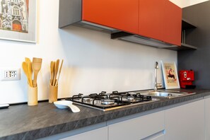 Une cuisine équipée d’une cuisinière à gaz, d’ustensiles en bois, d’un évier et de meubles de rangement modernes.
