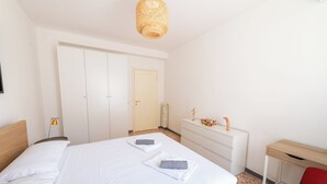 A neatly arranged bedroom with a bed, a dresser, a desk, and a red chair. - Casa Tripolitania (Rome)