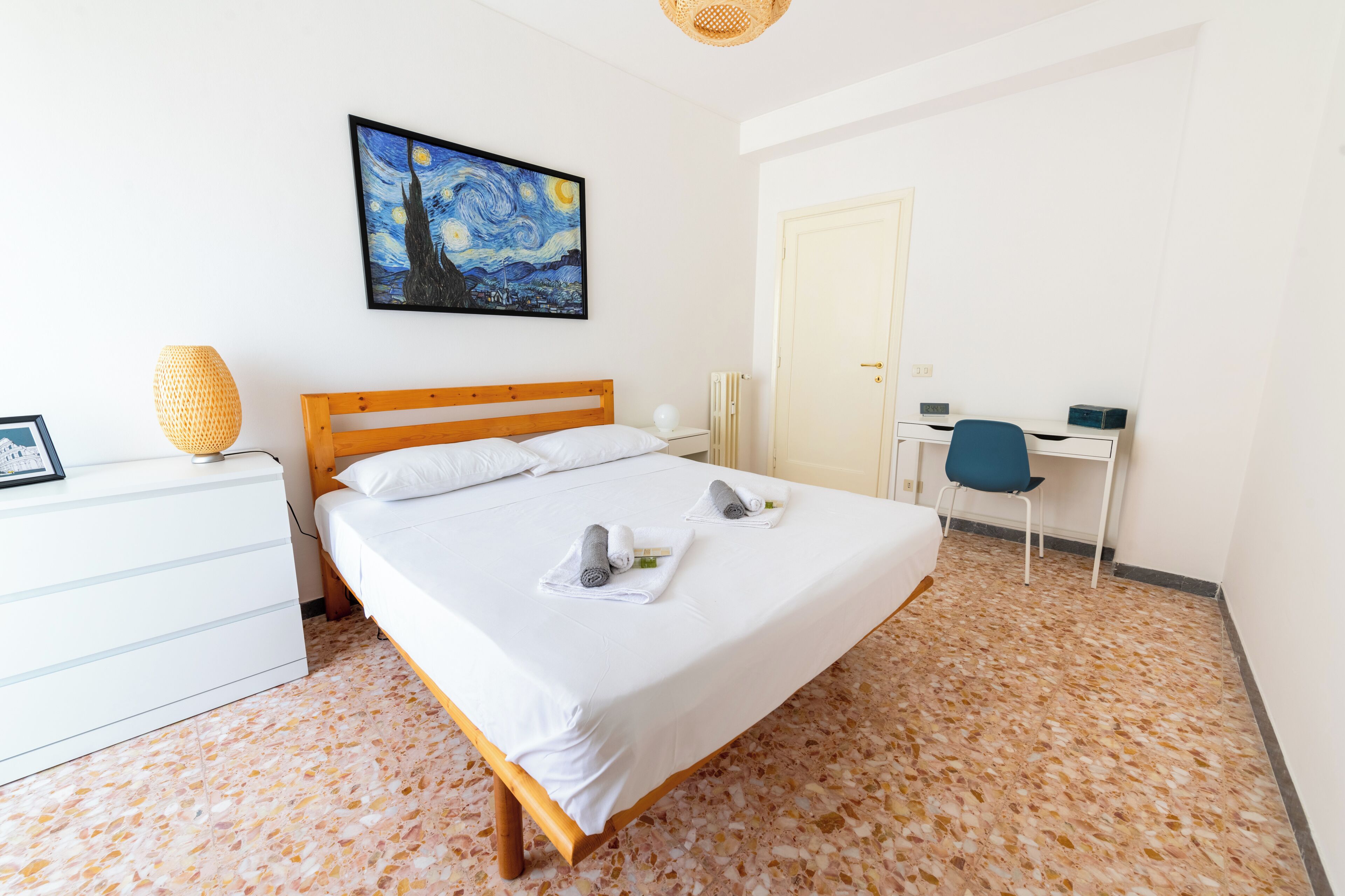 A neatly arranged hotel room with a bed, a desk, and a chair.