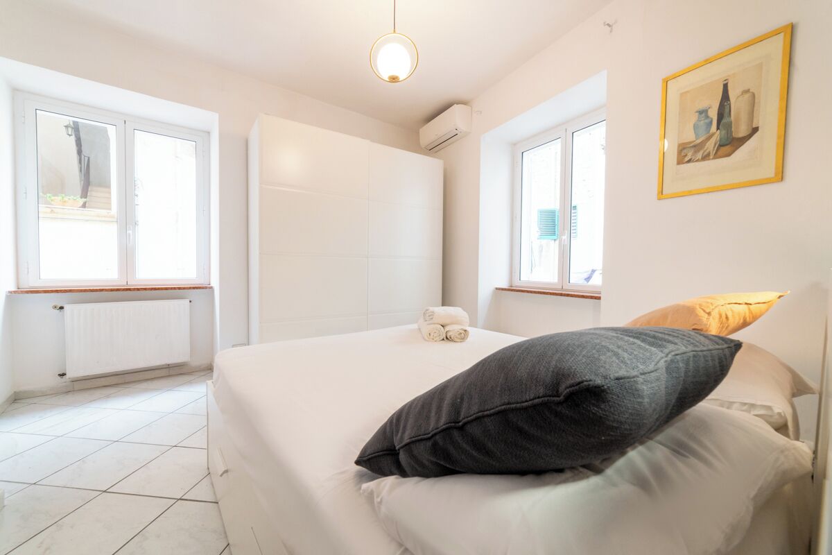 A bedroom with a bed, a radiator, a window, and a painting on the wall.