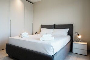 Una habitación de hotel moderna con una cama grande, una mesita de noche y una lámpara.