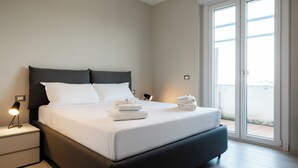 Una habitación de hotel moderna con una cama grande, lámparas de noche y vistas a través de un ventanal corredera.