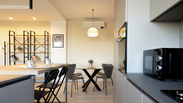Una cocina moderna con un refrigerador negro, una mesa de comedor con cuatro sillas y una lámpara colgante sobre la mesa.