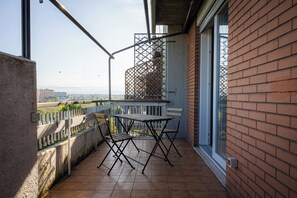 Un balcón con mesa y sillas, vista a la ciudad y un muro de ladrillo.