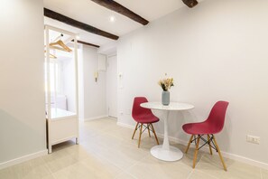 A modern room with a white table and two red chairs, a vase with dried flowers, and a wooden chair with a hanger. - La Stanza del Principe (Naples)