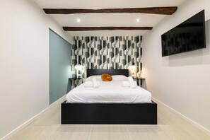 A modern bedroom with a bed, a patterned wallpaper, a mounted TV, and a unique ceiling design. - La Stanza del Principe (Naples)