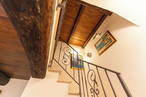 Uma escada de madeira com corrimão de metal, um quadro na parede e um lustre.