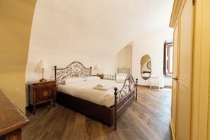 Un dormitorio con una cama de madera, dos mesitas de noche con lámparas, un espejo y un armario.