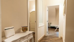 Un pasillo con un banco blanco, un cuenco colorido y una puerta que da a otra habitación.