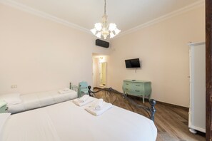 Ein Hotelzimmer mit zwei Betten, einem Fernseher, einem Kleiderschrank und einem Spiegel.