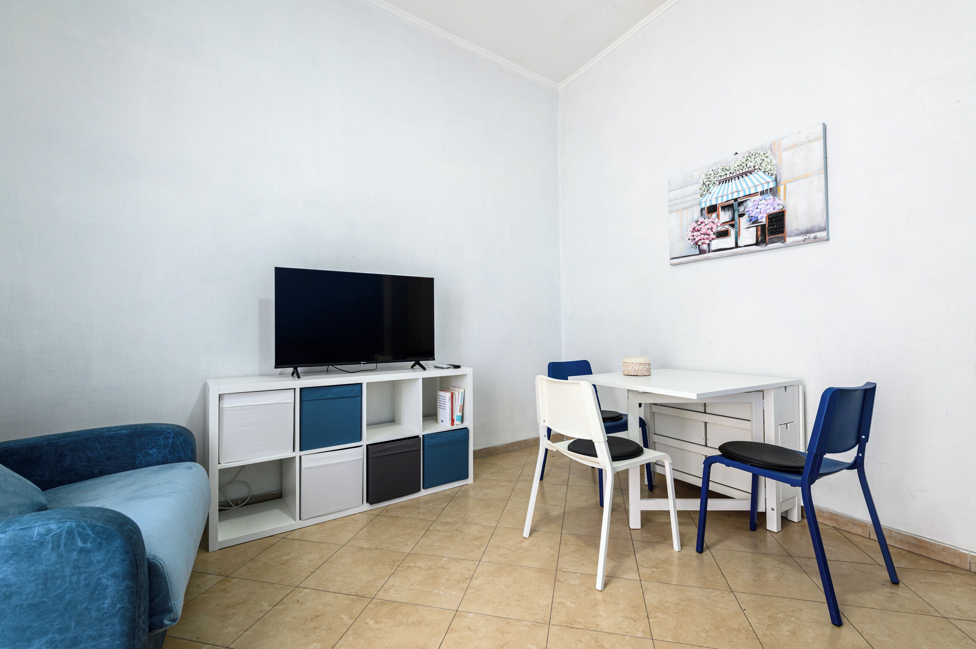 Una stanza con un letto, una scrivania con una sedia, una TV e un quadro appeso al muro.