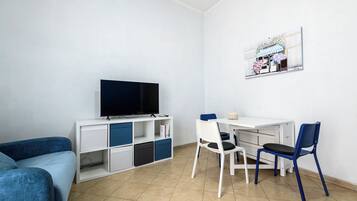 Una stanza con un letto, una scrivania con una sedia, una TV e un quadro appeso al muro.